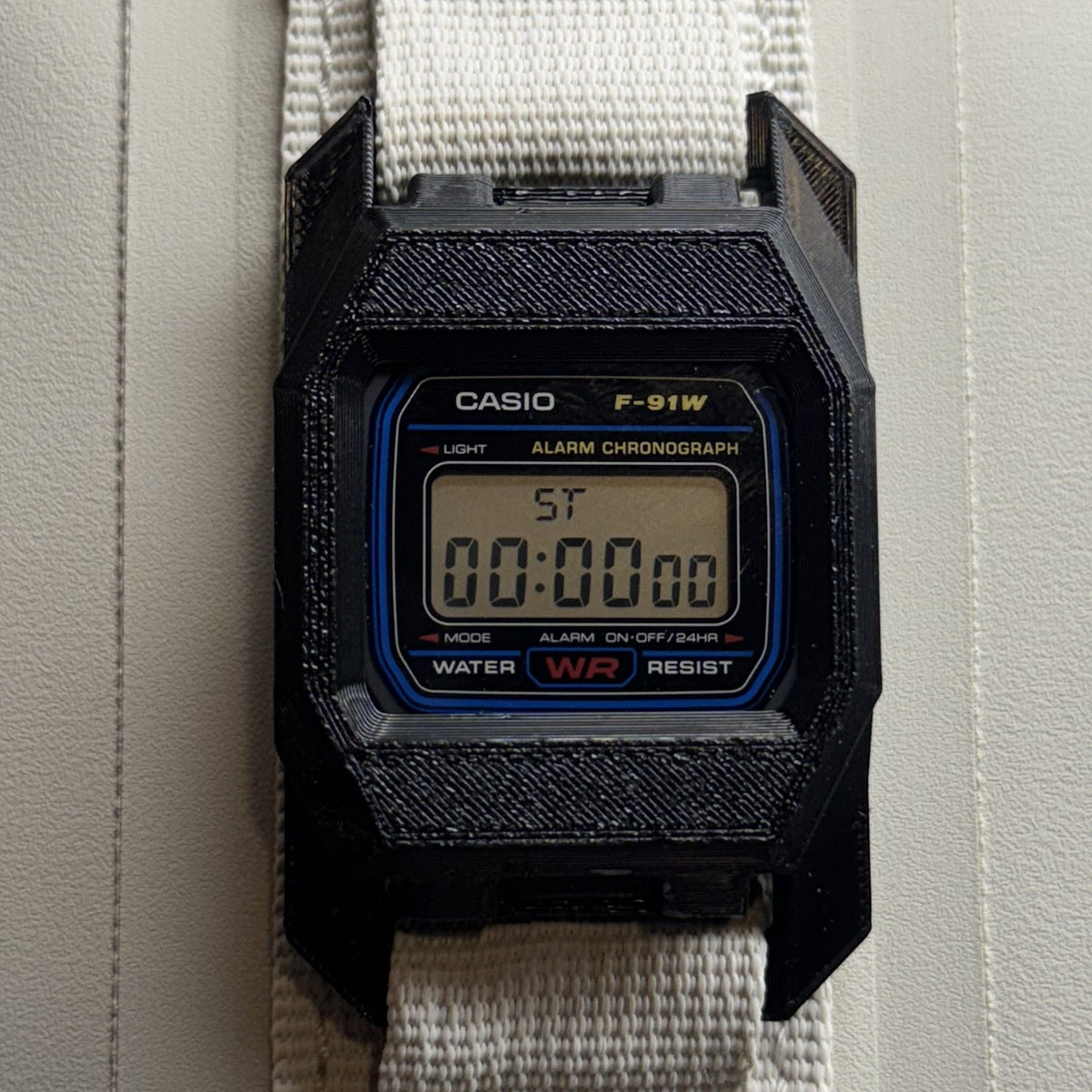 PROTOWORX F91 MOLLE Case in Stealth Black, mounted on MOLLE webbing with a Casio F-91W seated in the case